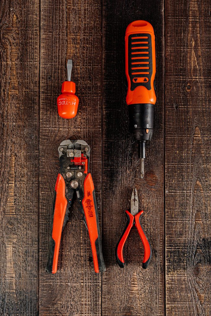 Image of tools that may be used by an electrical maintenence technician arranged on a wooden workbench